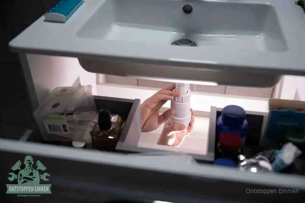 Een pompfles met zeep boven een wastafel, de heet water en afwasmiddel-methode om een vetprop in de afvoer los te maken in Emmen