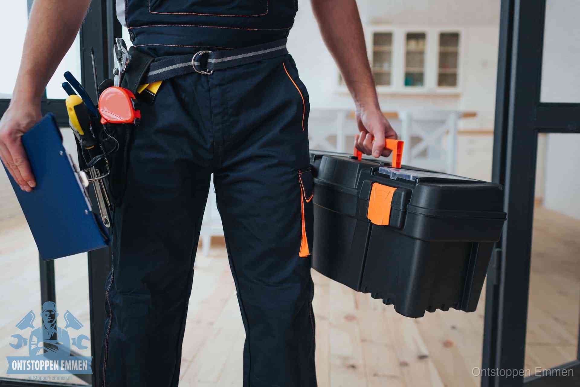 Een monteur met gereedschapsriem en klembord in een keuken, klaar om een transparante prijs voor het gootsteen ontstoppen in Emmen te geven