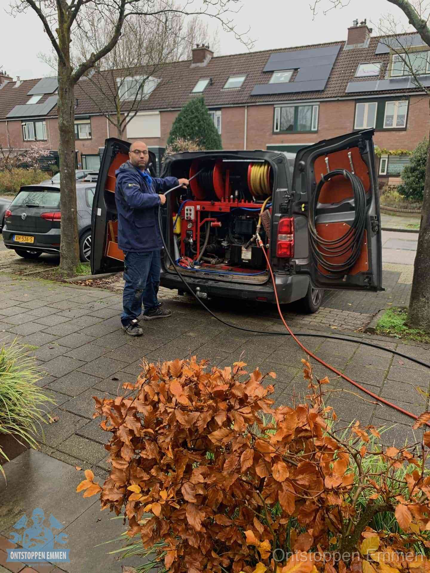 Monteur met rioolreinigingsbus levert rioolservice in de wijk in Emmen