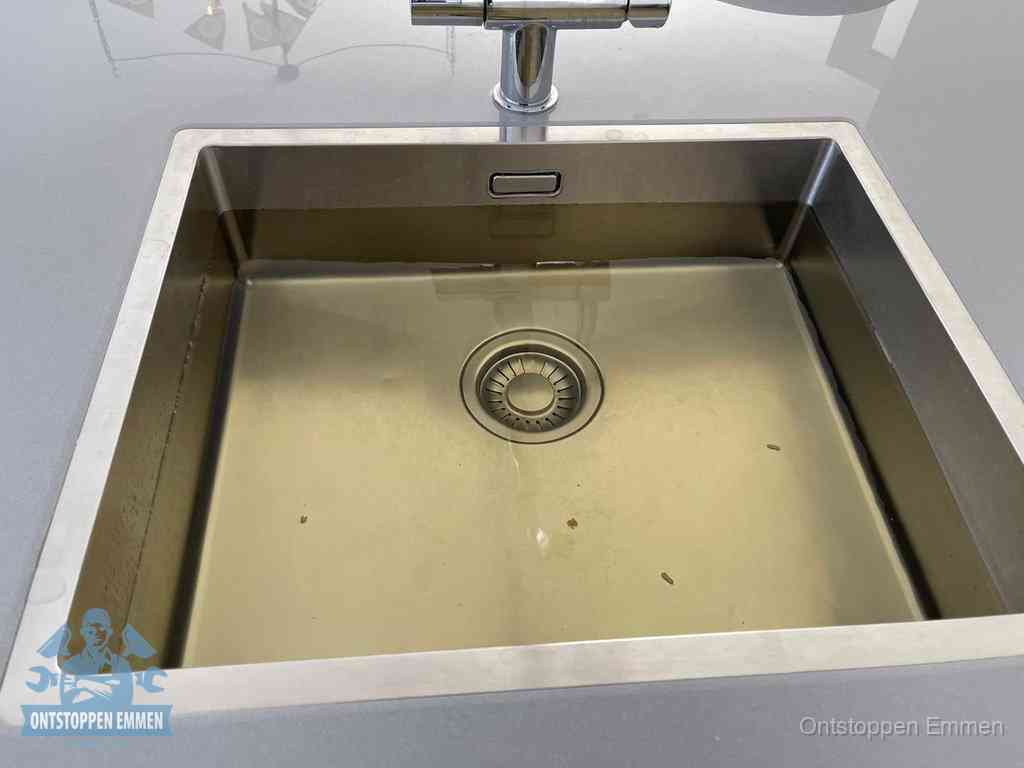 Stilstaand water in een rvs spoelbak dat niet wegloopt, een duidelijk signaal van een gootsteenverstopping in Emmen