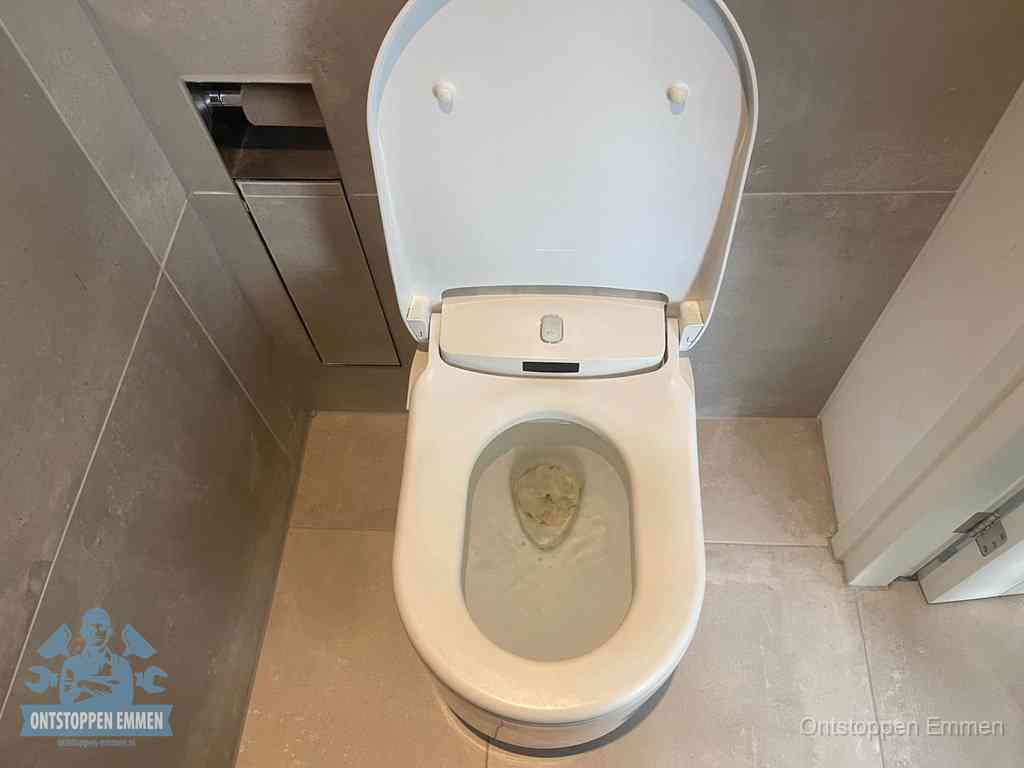 Een wit hangtoilet waarin een prop wc-papier op het water blijft drijven, een duidelijk signaal van een verstopte wc in Emmen