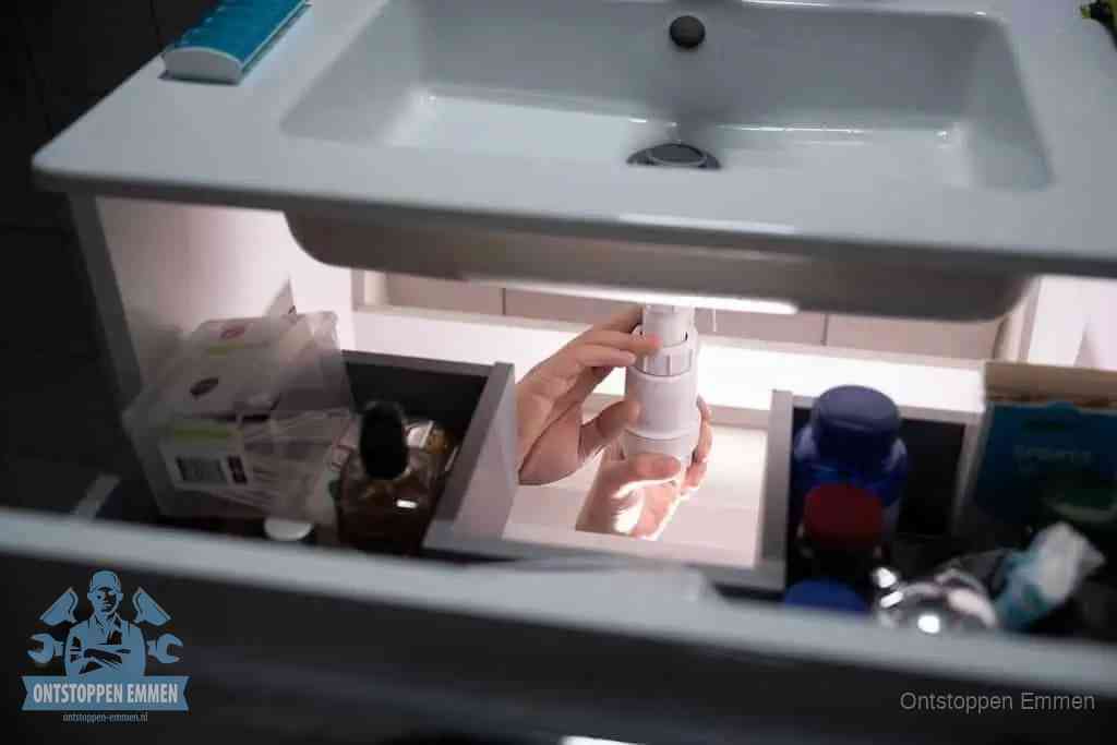 Een pompfles met zeep boven een wastafel in de toiletruimte, de warm water en afwasmiddel-methode om de wc te ontstoppen in Emmen