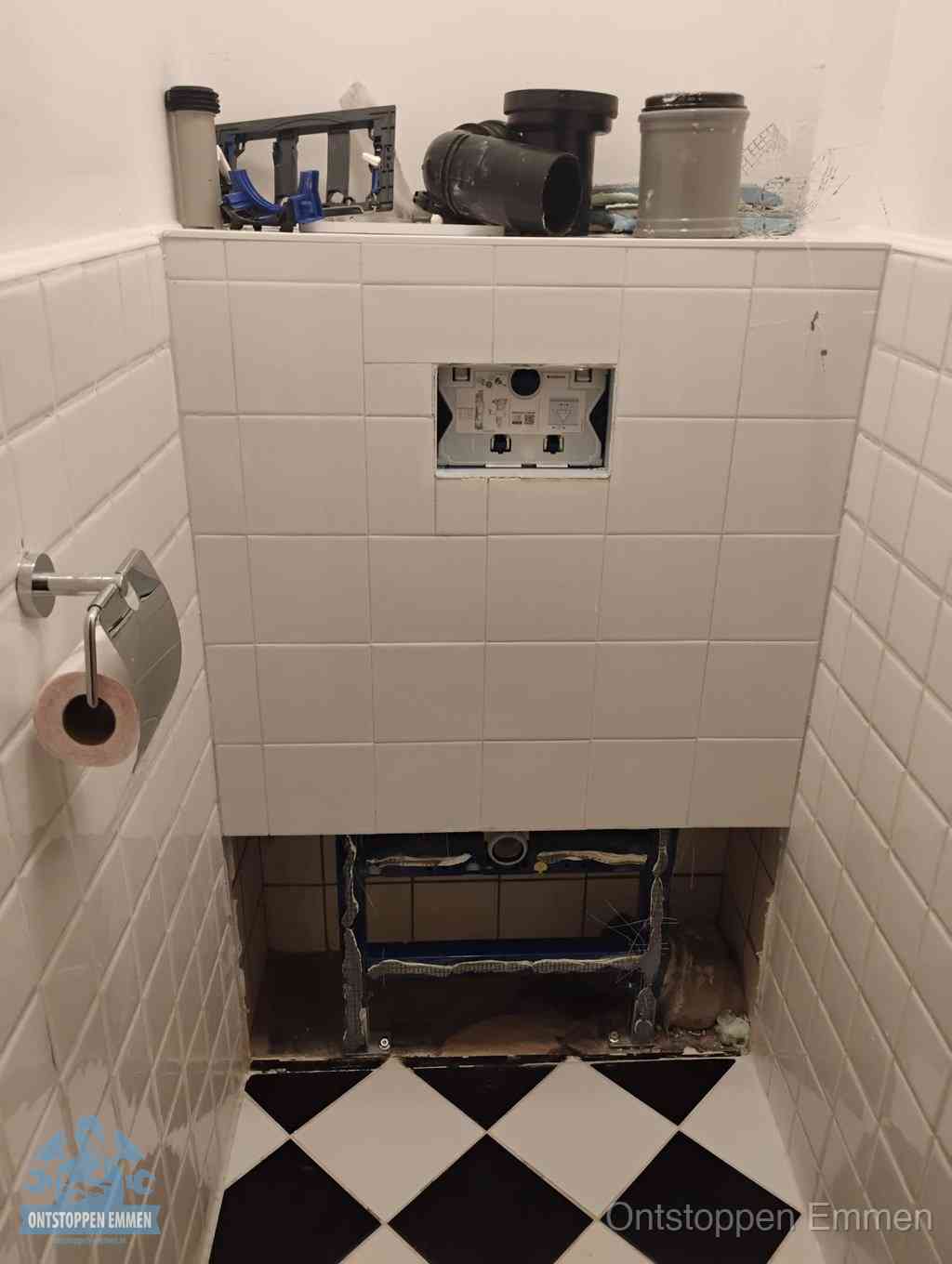 Een toiletruimte waar het hangtoilet en de inbouwreservoir-onderdelen zijn vrijgelegd voor onderhoud, periodiek nazicht voorkomt een wc-verstopping in Emmen
