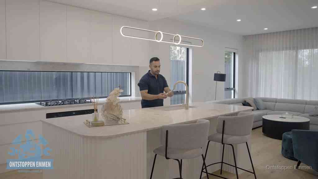 Een bewoner bij de keukenspoelbak die zelf aan de slag gaat met een verstopte gootsteen in Emmen